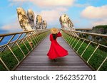 Asian woman in Vietnamese national costume on the Golden Bridge with Two Giant Hands, a viewpoint at a popular tourist attraction in Ba Na Hills Resort, Danang, Vietnam.