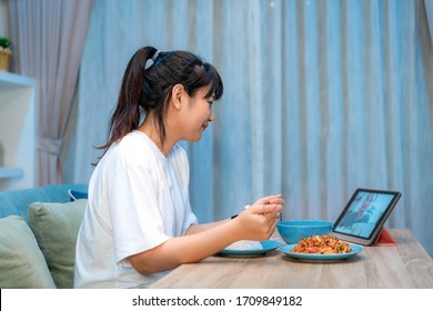 Asian Woman Virtual Happy Hour Meeting Dinner And Eating Food Online Together With Her Boyfriend In Video Conference With Tablet For A Online Meeting In Video Call For Social Distancing
