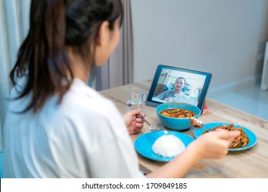 Asian Woman Virtual Happy Hour Meeting Dinner And Eating Food Online Together With Her Boyfriend In Video Conference With Tablet For A Online Meeting In Video Call For Social Distancing
