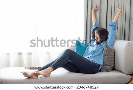 Asian woman wake up after sleep and relax on sofa bed in her living room in her condomenium in her holiday on weekend