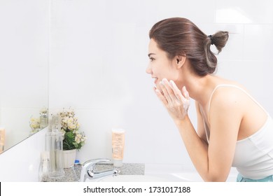 Asian Woman Wash Her Face In The Bathroom Before Shower.