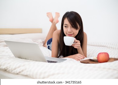 Asian Woman Watching On Laptop Computer And Having Breakfast In Bed