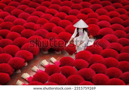Asian woman wearing ao dai dress with Incense sticks drying outdoor in Hanoi, Vietnam.