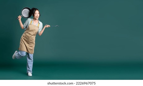 Asian woman wearing apron and holding a pan