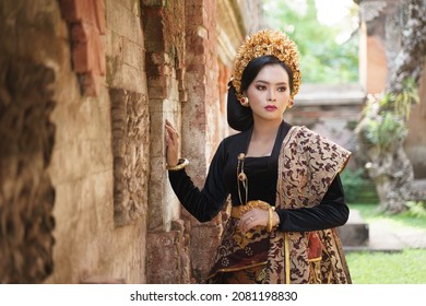 Asian woman wearing Balinese kebaya next to a relief wall