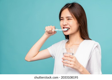 Asian Woman Wearing Braces With Brushing Teeth And Holding Water Glass, Towel On The Shoulder On Blue Background, Concept Oral Hygiene And Health Care.