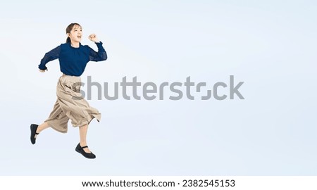 Asian woman wearing casual wear jumping energetically. Wide angle visual for banners or advertisements.