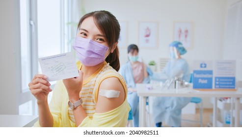 asian woman wearing face mask receiving coronavirus vaccine then she shows her arm and COVID-19 vaccination record to you in hospital - Powered by Shutterstock