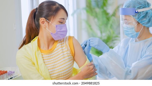 Asian Woman Wearing Face Mask Receiving Coronavirus Vaccine In Hospital