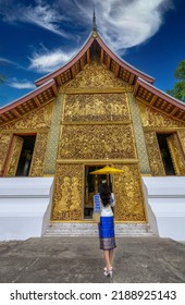 Asian Woman Wearing A Lao National Costume Visits Wat Xieng Thong In Luang Prabang, Laos