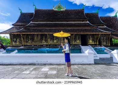 Asian Woman Wearing A Lao National Costume Visits Wat Xieng Thong In Luang Prabang, Laos