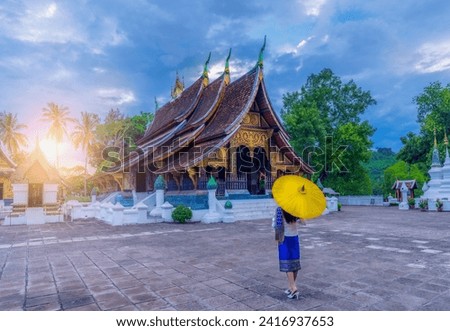 Asian woman wearing a Lao national costume visits Wat Xieng Thong in Luang Prabang, Laos