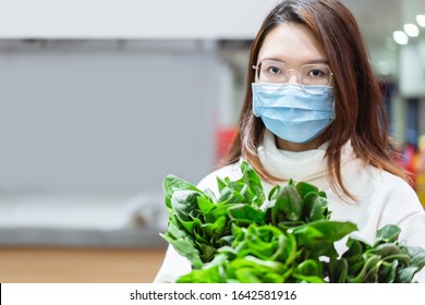 Asian woman wearing mask is buying vegetables