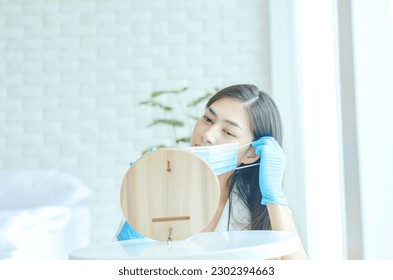 Asian woman wearing a mask, headphones and blue rubber gloves. She works as a call center. - Powered by Shutterstock