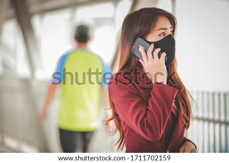 Asian woman wearing mask and talking on the mobile phone for protect pm2.5 and cough with Covid-19 virus outbreak in public.
