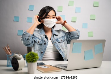 Asian Woman Wearing Protective Face Mask Working On A Laptop At Home Office. WFH. Work From Home. Prevention Coronavirus COVID-19 Concept.