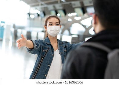 Asian Woman Wearing Protective Mask Running To Embrace Friend Or Boyfriend At Arrival Gate In Airport Terminal. Welcome Back Home From Study Or Working Abroad During Coronavirus Pandemic