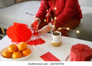 Asian woman wearing red clothes making paper craft red Chinese new year lantern or Lunar New Year decorations Chinese New Year Celebrations for good luck.