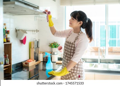 Asian Woman Wearing Rubber Protective Gloves Cleaning Kitchen Cooking Hood In Her Home During Staying At Home Using Free Time About Their Daily Housekeeping Routine.