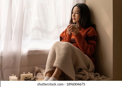 An Asian Woman Wearing A Sweater Inhaled The Scent And Drank The Winter Morning Coffee. She Looked At The View From The Large Window On Vacation.