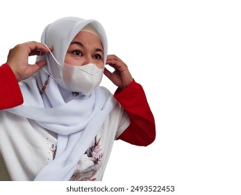 Asian woman wearing a white hijab, red and white t-shirt, wearing a white face mask, isolated on white background. - Powered by Shutterstock