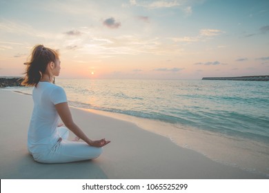 Asian woman wearing white sportswear practicing yoga Lotus pose to meditation on the beach in Maldives at sunset,Feeling so comfortable and relax in holiday,Healthy with Yoga Concept - Powered by Shutterstock