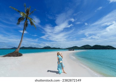 Asian woman wears a dress and travels to the beach in the summer alone on her vacation. At andaman sea Laem Had Beach, Koh Yao Yai, Phang Nga, Thailand.