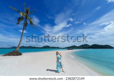 Asian woman wears a dress and travels to the beach in the summer alone on her vacation. At andaman sea Laem Had Beach, Koh Yao Yai, Phang Nga, Thailand.