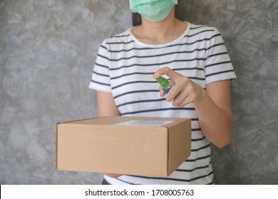 Asian woman wears mask using spray alcohol sanitizer cleaning parcel post, to prevent the virus and bacterias from postal sender, she protects herself and her family from viruses.woman giving package  - Shutterstock ID 1708005763