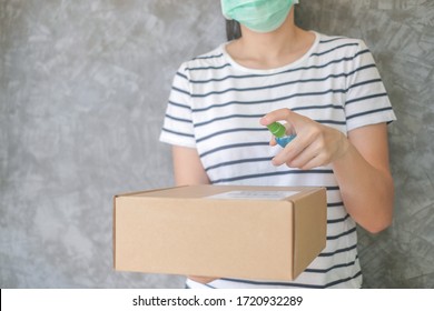 Asian woman wears mask using spray alcohol sanitizer cleaning parcel post, to prevent the virus and bacterias from postal sender, she protects herself and her family from viruses.woman giving package - Shutterstock ID 1720932289