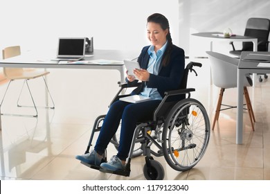 Asian Woman In Wheelchair Working With Tablet PC In Office