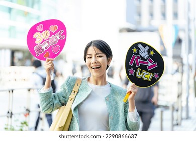 Asian woman who came to see a concert with cheering fans. Japanese translation: "shoot with bang!","stare for 3 seconds"