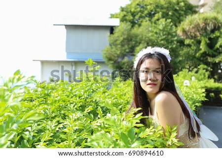 Asian woman who wear white crown stand with trees look at camera