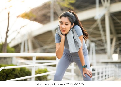 Asian woman wiping sweat on face and neck during exercise in the city at sunrise. Young asian female take a break from training before workout, cardio. Healthy and active lifestyle concept. - Powered by Shutterstock