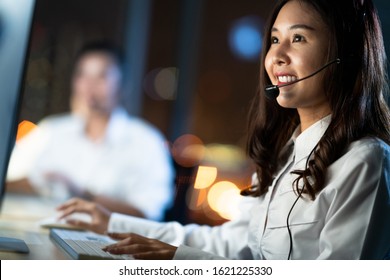 Asian Woman Work As Customer Support Service Or Call Center Phone Operator, Using Desktop Computer And Microphone Headset, Late Night Shift. Overtime Office Life, Telemarketing Or Sales Job Concept