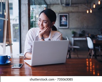 Asian woman working with laptop in coffee shop.