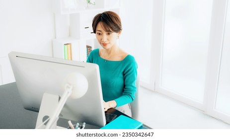 Asian woman working on computer in casual office.
