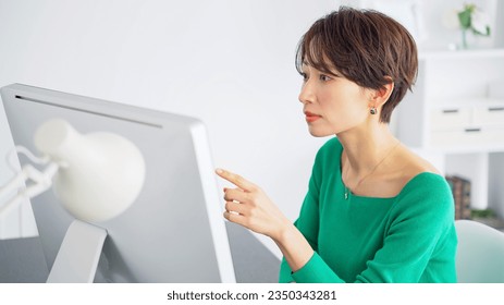 Asian woman working on computer in casual office.