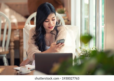 Asian Woman Working With Phone And Laptop At Coffee Shop