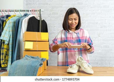 Asian Woman Working Taking Photo To Shoes With Smart Phone For Post To Sell Online On The Internet, Start Up Small Business Owner Work At Home Office