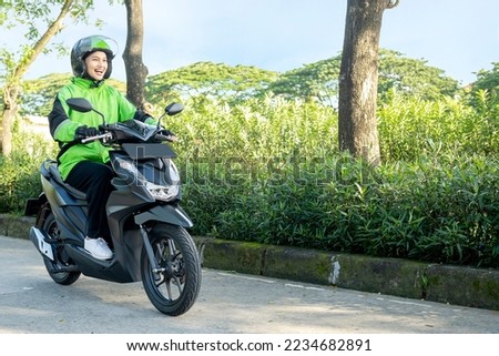 Asian woman works as a motorcycle taxi driver on the street