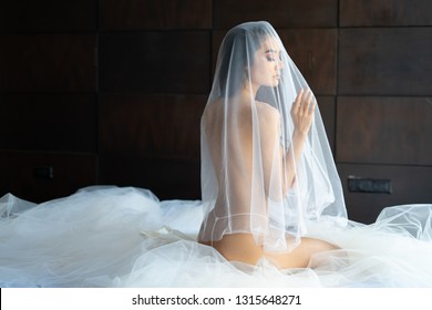 Asian woman wrapped in white fabric, beautiful slim.Naked woman art in white light transparent dress posing on a bed.
