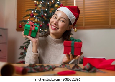 Asian Woman Wrapping Christmas Gift Box Under X' Mas Tree In Home Living Room.