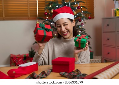 Asian Woman Wrapping Christmas Gift Box Under X' Mas Tree In Home Living Room.