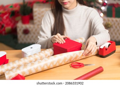 Asian Woman Wrapping Christmas Gift Box Under X' Mas Tree In Home Living Room.