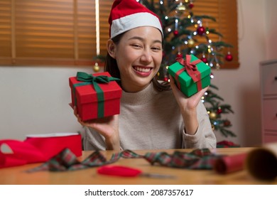 Asian Woman Wrapping Christmas Gift Box Under X' Mas Tree In Home Living Room.