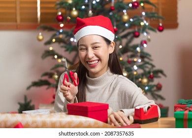 Asian Woman Wrapping Christmas Gift Box Under X' Mas Tree In Home Living Room.