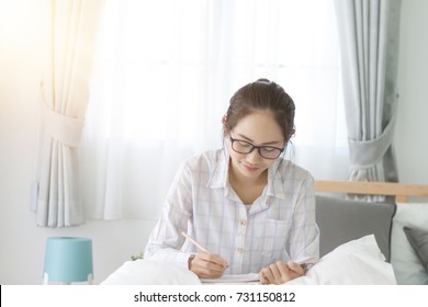 Asian Woman Writing On Bed.