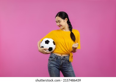 Asian Woman In Yellow T-shirt Holding Football Ball To Cheering The Soccer Game On The Pink Screen Background.