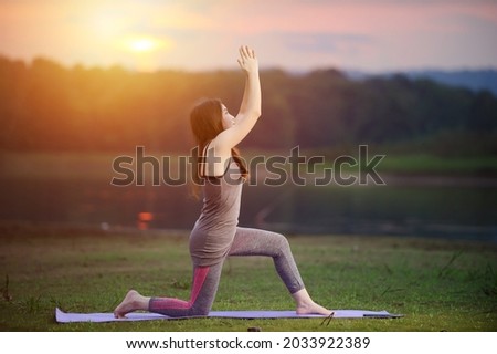 asian woman with yoga posture in nature with  mountain background  at sunset